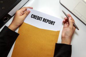 Businesswoman opening Credit report document in letter envelope.