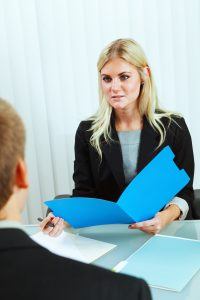 Subject: A business meeting and Interview. A human resource recruitment officer reading the file and resume of a job applicant in a job interview.