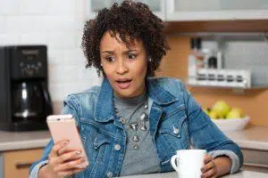 African American woman shocked what she sees on mobile phone