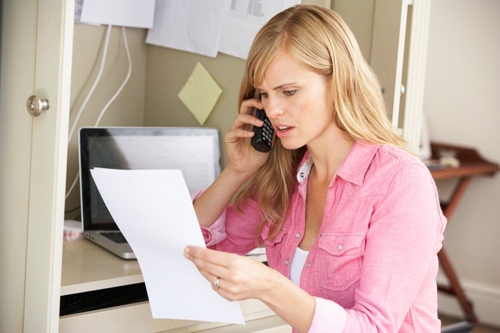 Woman Working In Home Office On Phone Discussing Document On Telephone