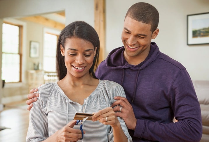 Young couple cutting down a credit card with scissors